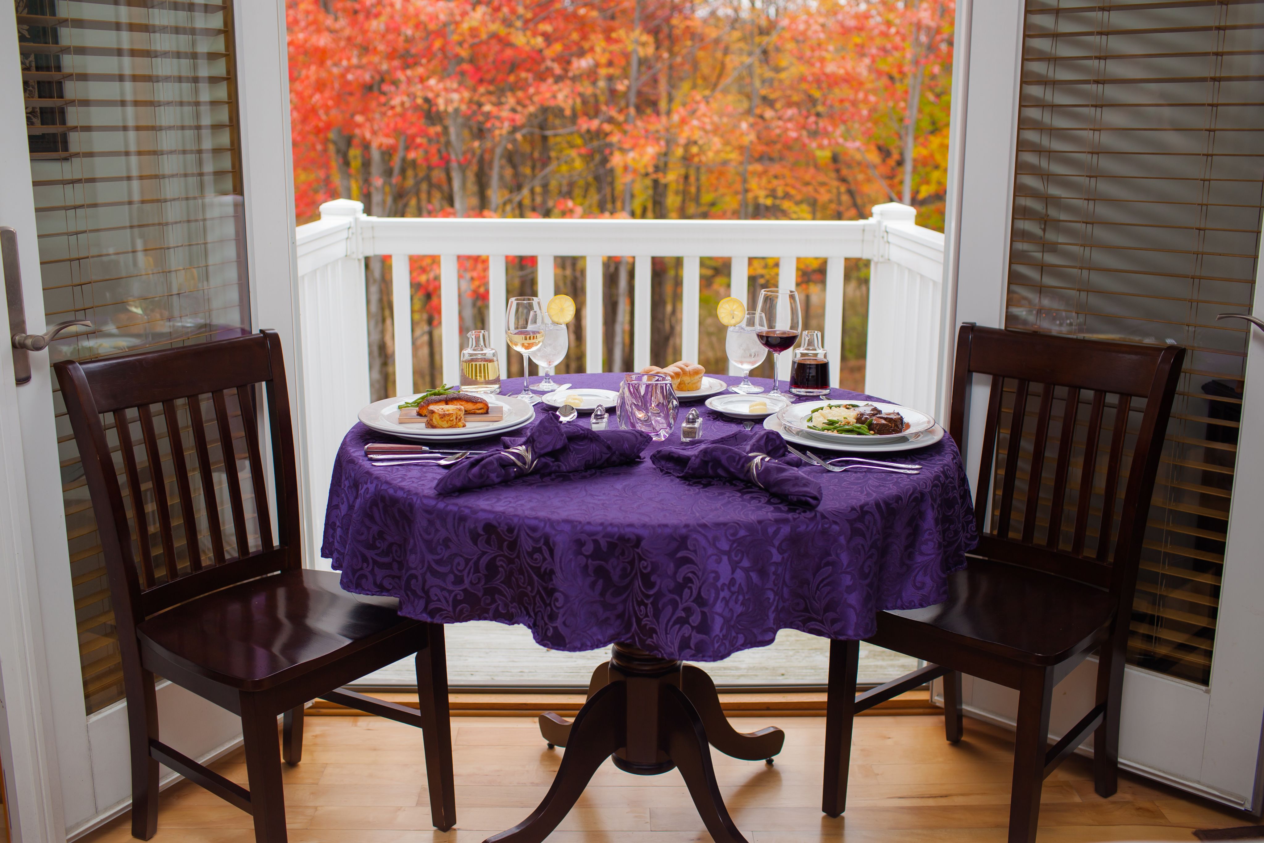 A BEAUTIFUL LINEN DRAPED TABLE IN A GUEST ROOM OVERLOOKING STUNNING FALL FOLIAGE